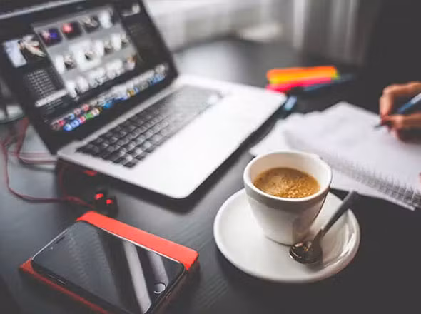 Macbook auf Schreibtisch mit Kaffe bei Website Erstellung